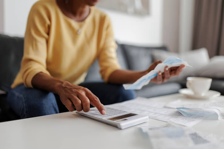 Close up of anadult woman checking her speeding ticket at home, sitting in her living room. She has a worried expression