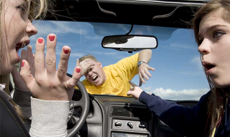 Two young female drivers looking at eachother as they hit a man in a yellow shirt holding his forehead.