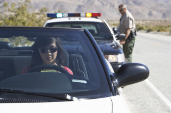 Lady getting pulled over in a convertible by a police officer.