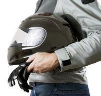 Person in a grey jaket holding their black motorcycle helmet.