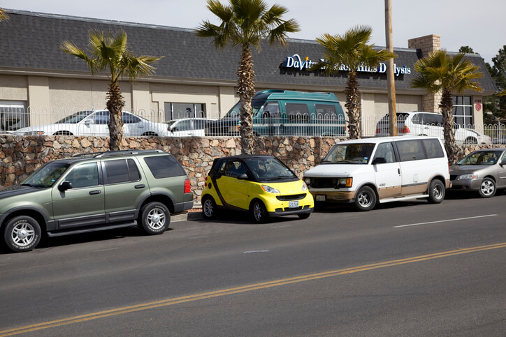 A small yellow coupe is parked sideways in a parallel parking space.