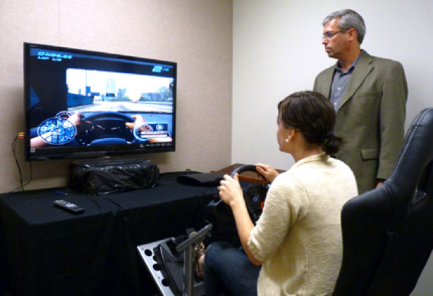 Lady behind the wheel of a driving video game.