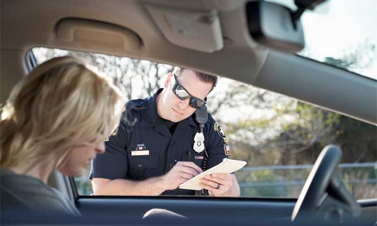 Police officer writing a blonde woman a ticket who is sulking.