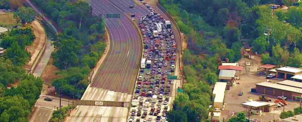 Am overhead shot of a backed up interstate with hundreds of cars on it.